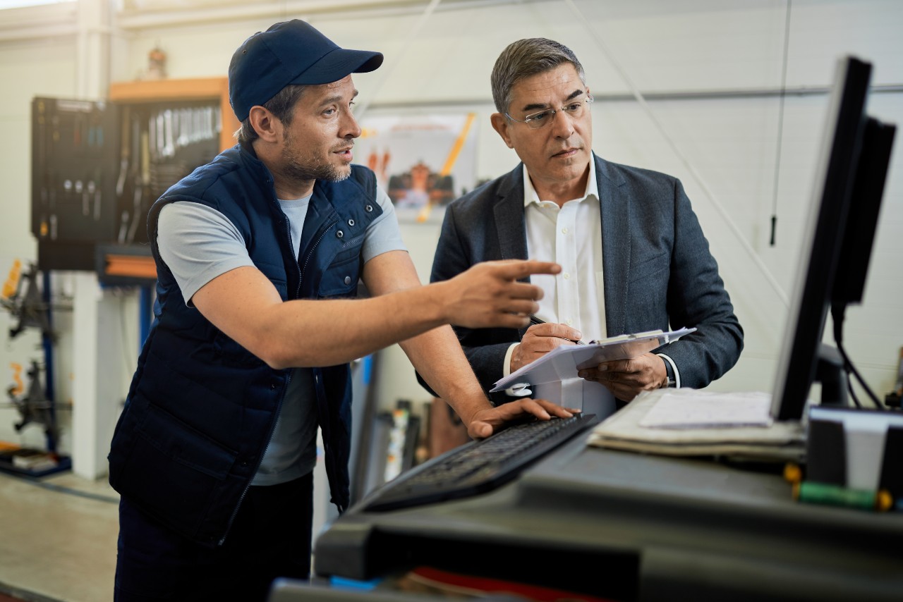 two staff member talking while using computer while performing maintenance work